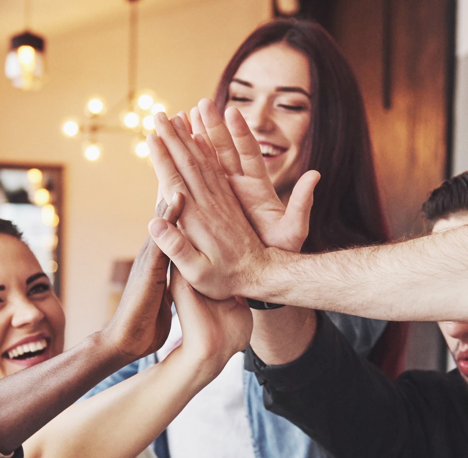 Group of people smiling and giving each other a high five all at once