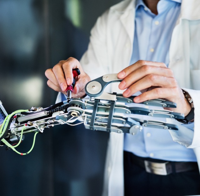 Man in a lab coat working on a robot arm