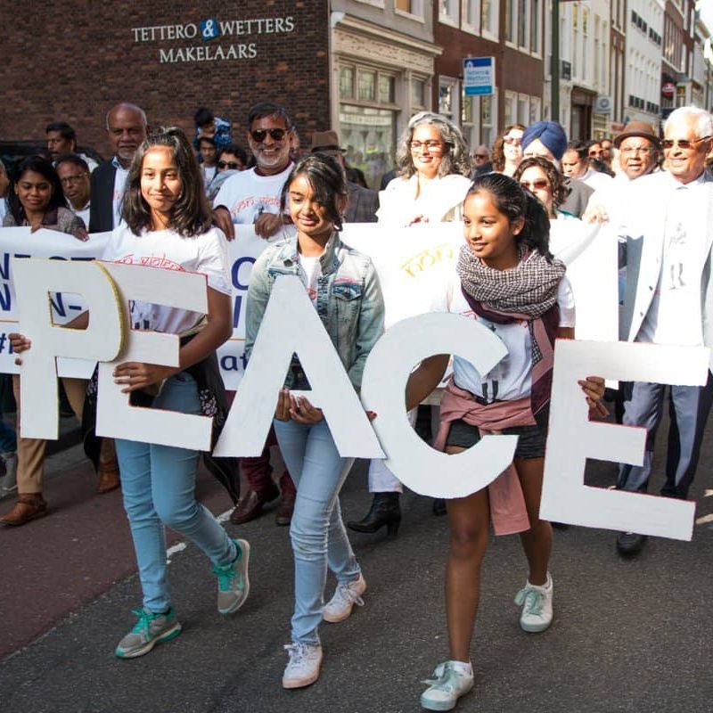 People Marching with young women holding letters that spell out PEACE