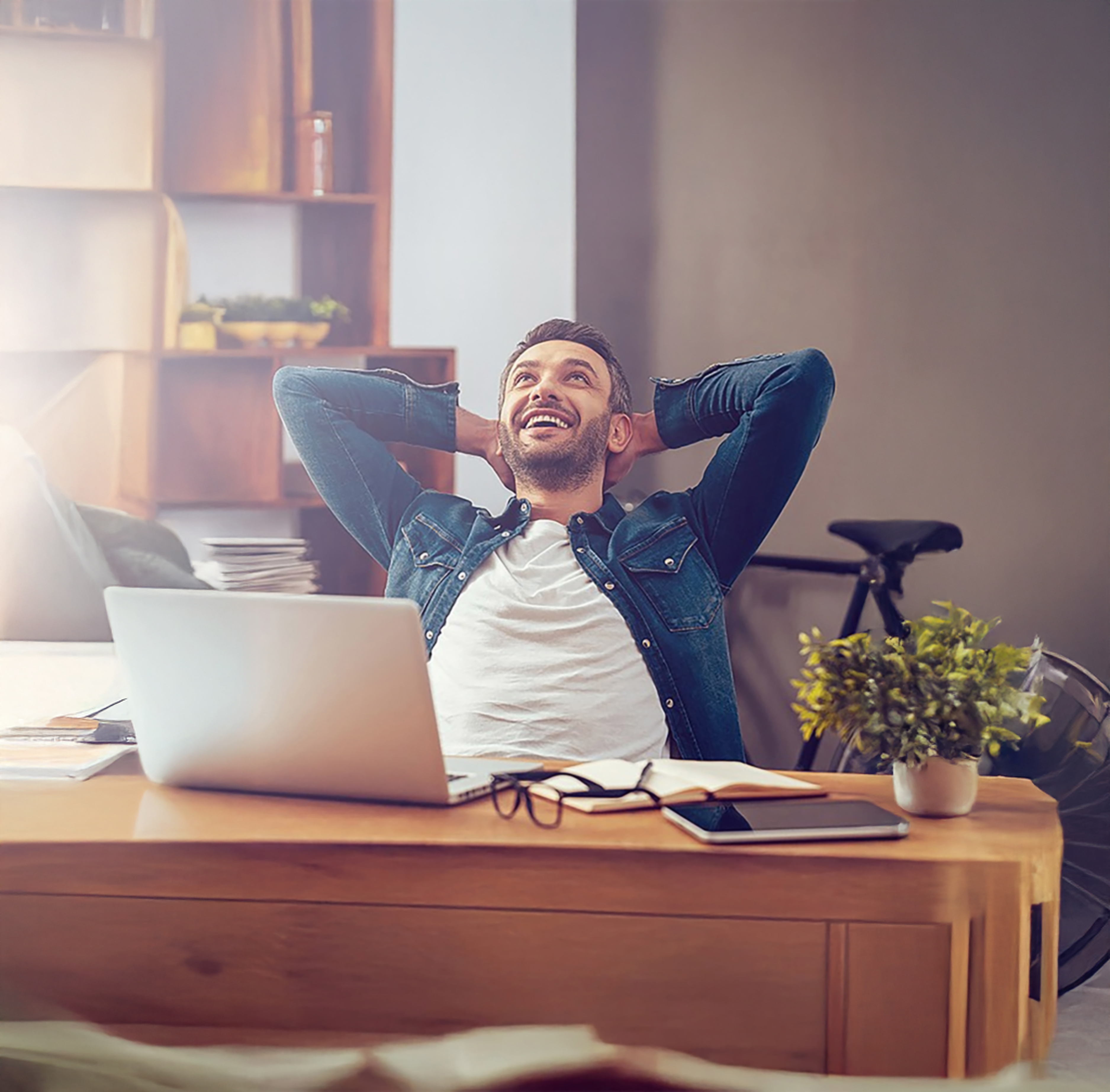A young professional relaxing behind a desk after a success